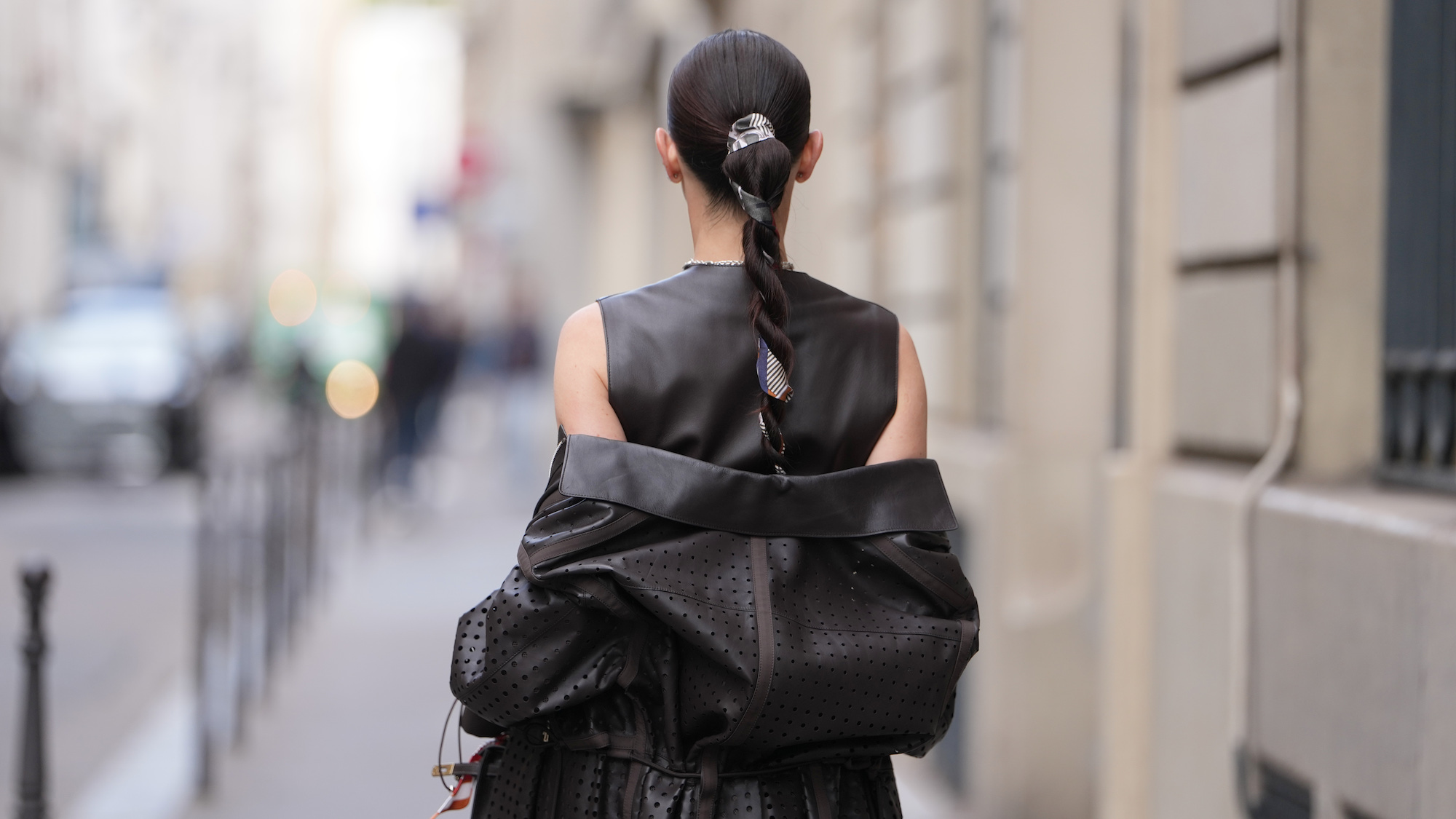 best hair ties damage-free Woman wears sleek dark brown hair pulled into a long braided ponytail with a centre part and a patterned silk scarf woven through the braid