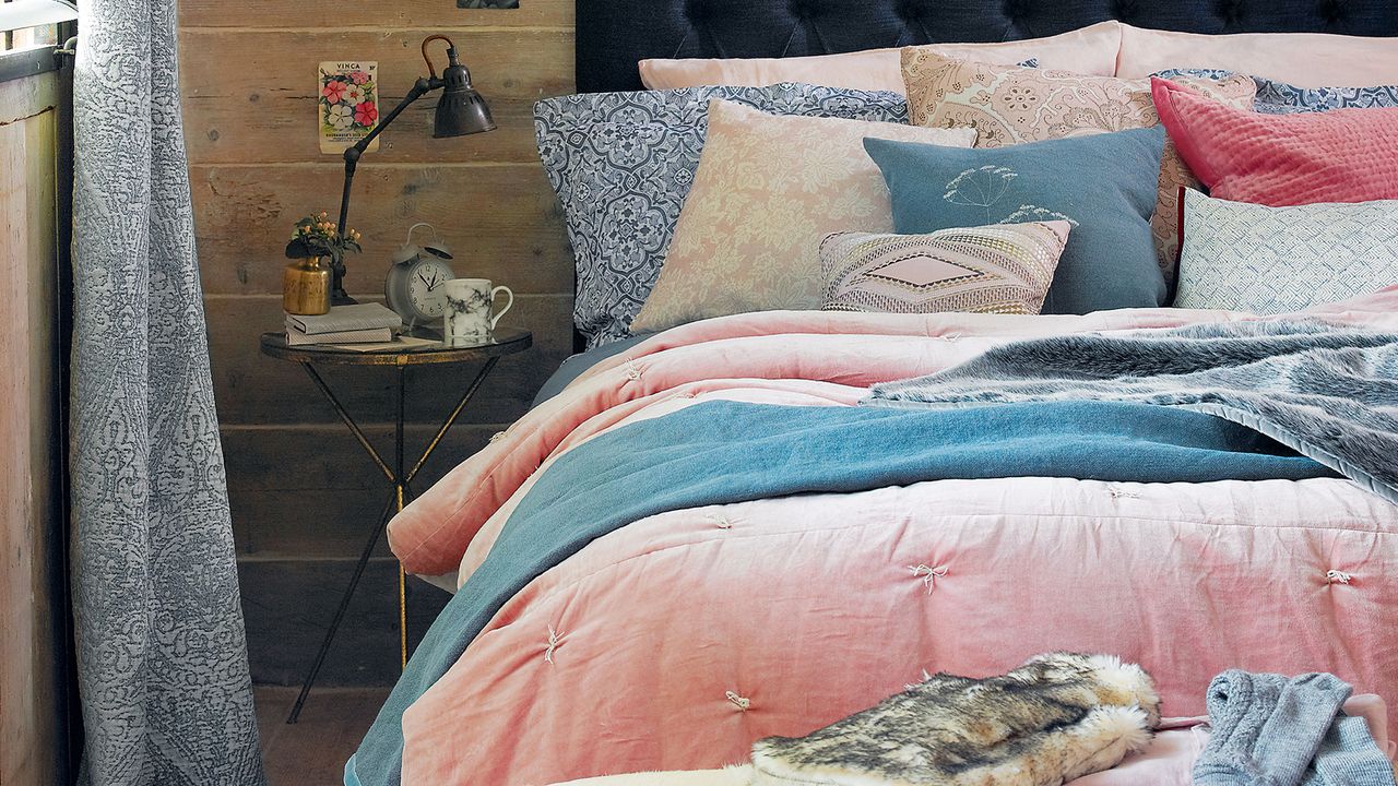 cosy bed with pink duvet and lots of cushions in blue and pink