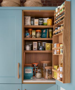 A light blue pantry with natural wood shelving