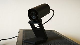 A black HP 965 4K webcam sitting on top of a black tower PC