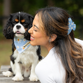 Woman wearing a blue daisy-print claw clip next to her dog who is wearing a matching bandana round its neck