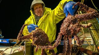A fisherman holding a pair of king crabs in an episode of Deadliest Catch