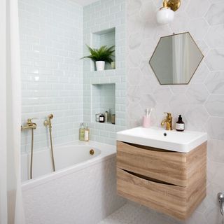 bathroom with hexagonal and rectangular tile wall bathtub and wooden drawers