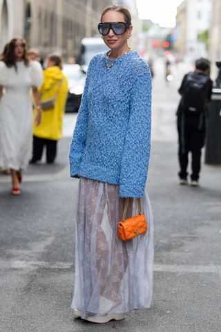 Woman wearing blue jumper and black lace skirt GettyImages-2165954585