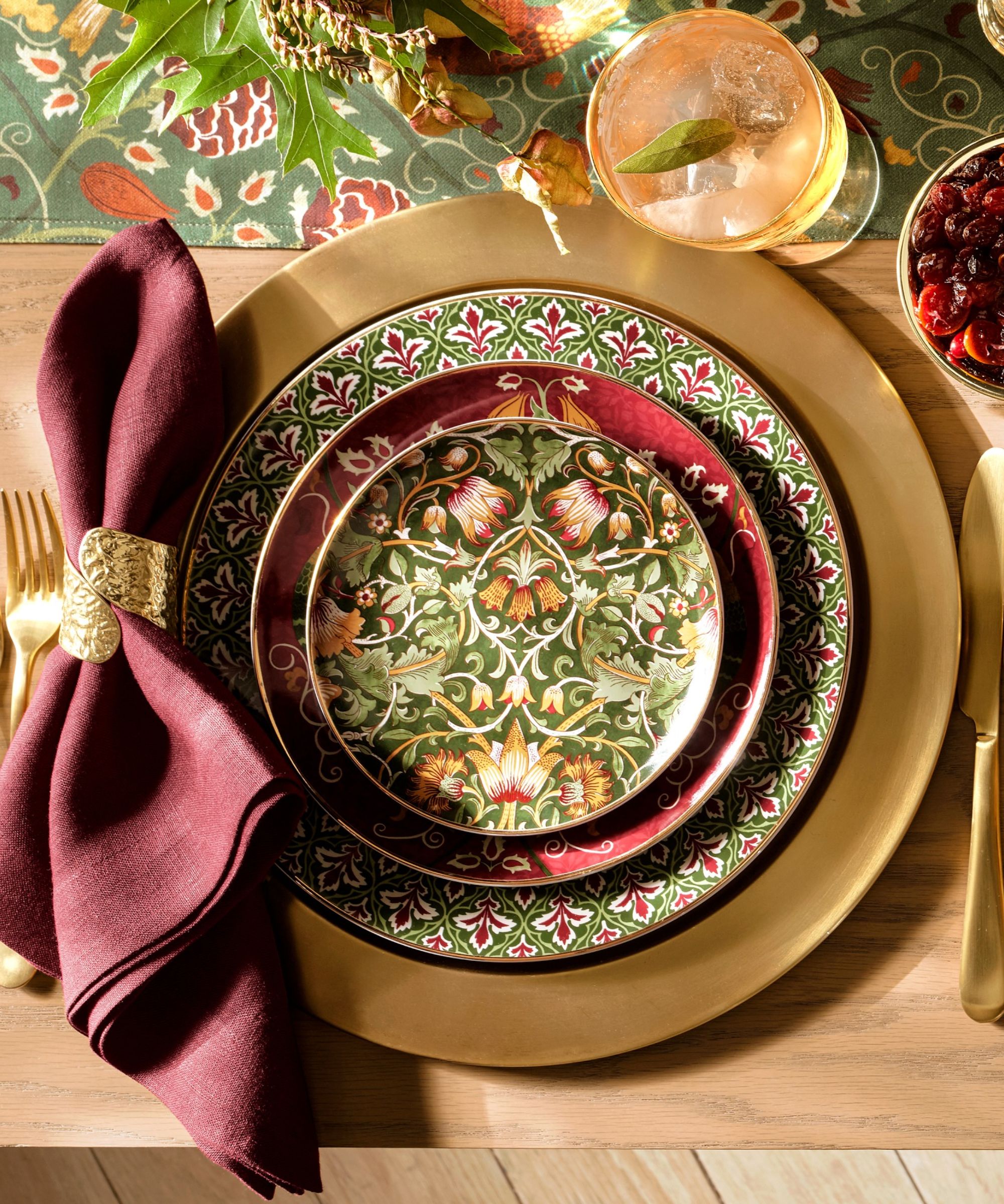 Table with gold charger plate, gold cutlery, red napkin, and red and green Morris &amp;amp; Co plates