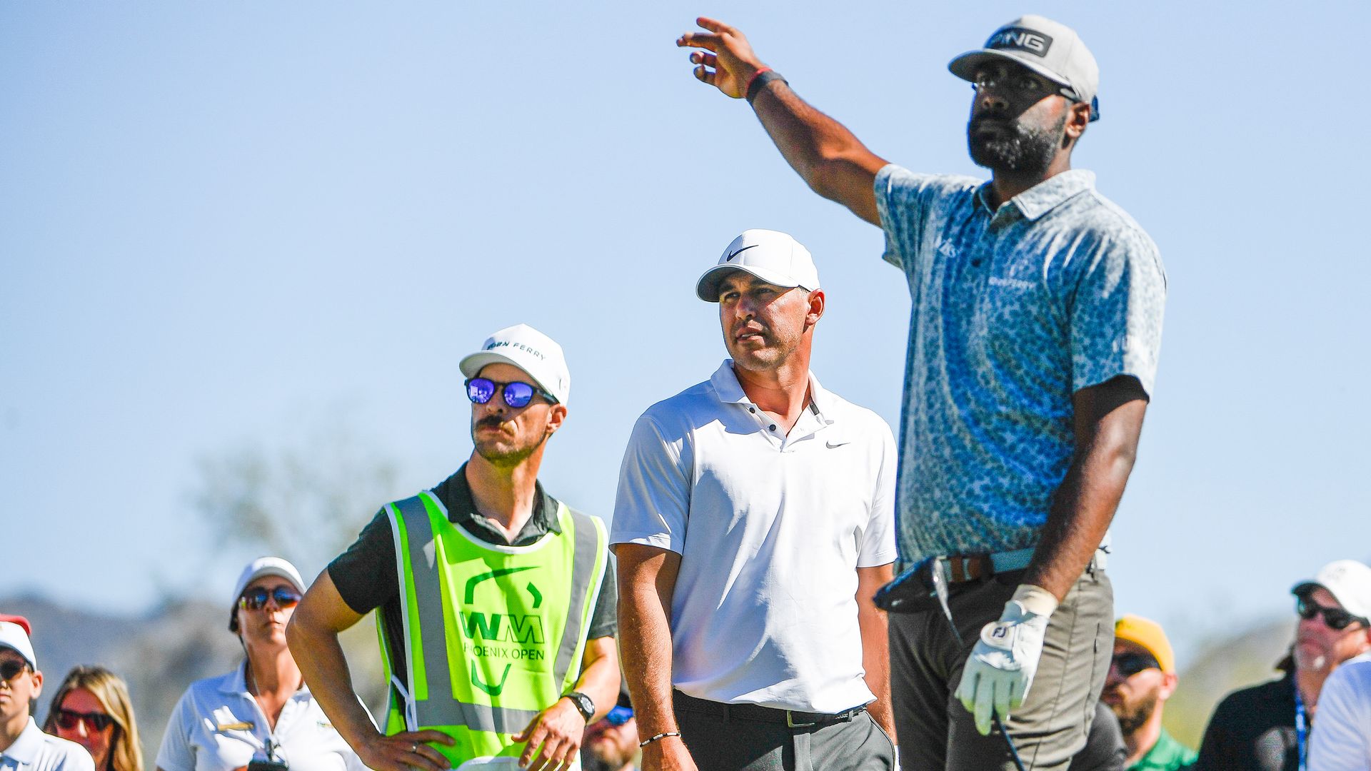 Brooks Koepka watches as Sahith Theegala signals his driver right at the third hole during the final round of the WM Phoenix Open at TPC Scottsdale on February 13, 2022