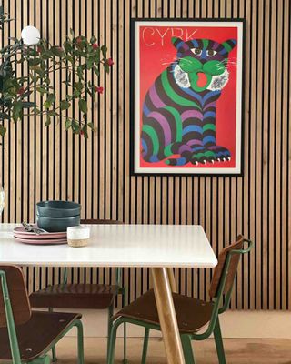 A red and green vintage print behind matching green dining chairs