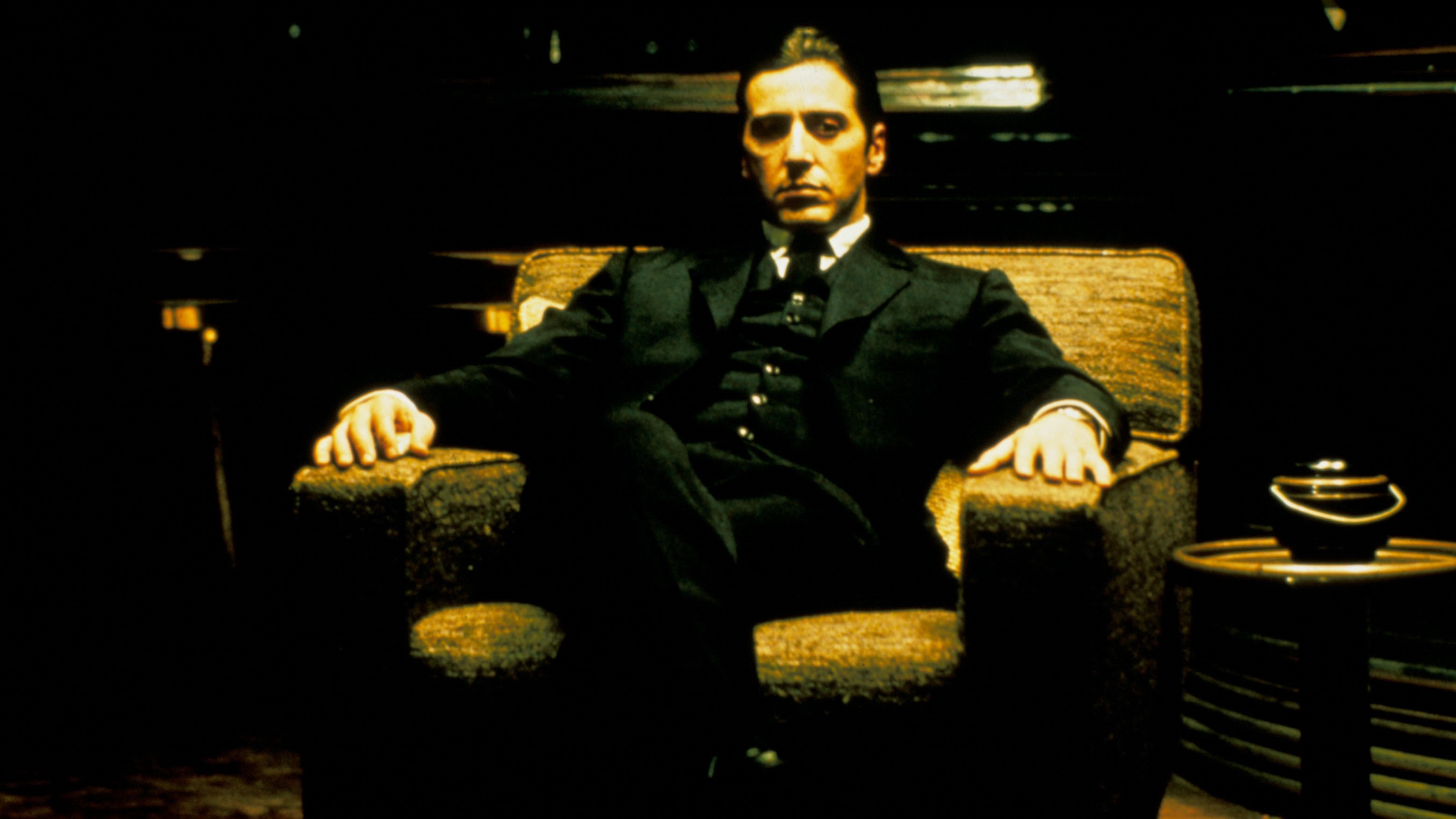 Al Pacino sitting in a chair in The Godfather Part II