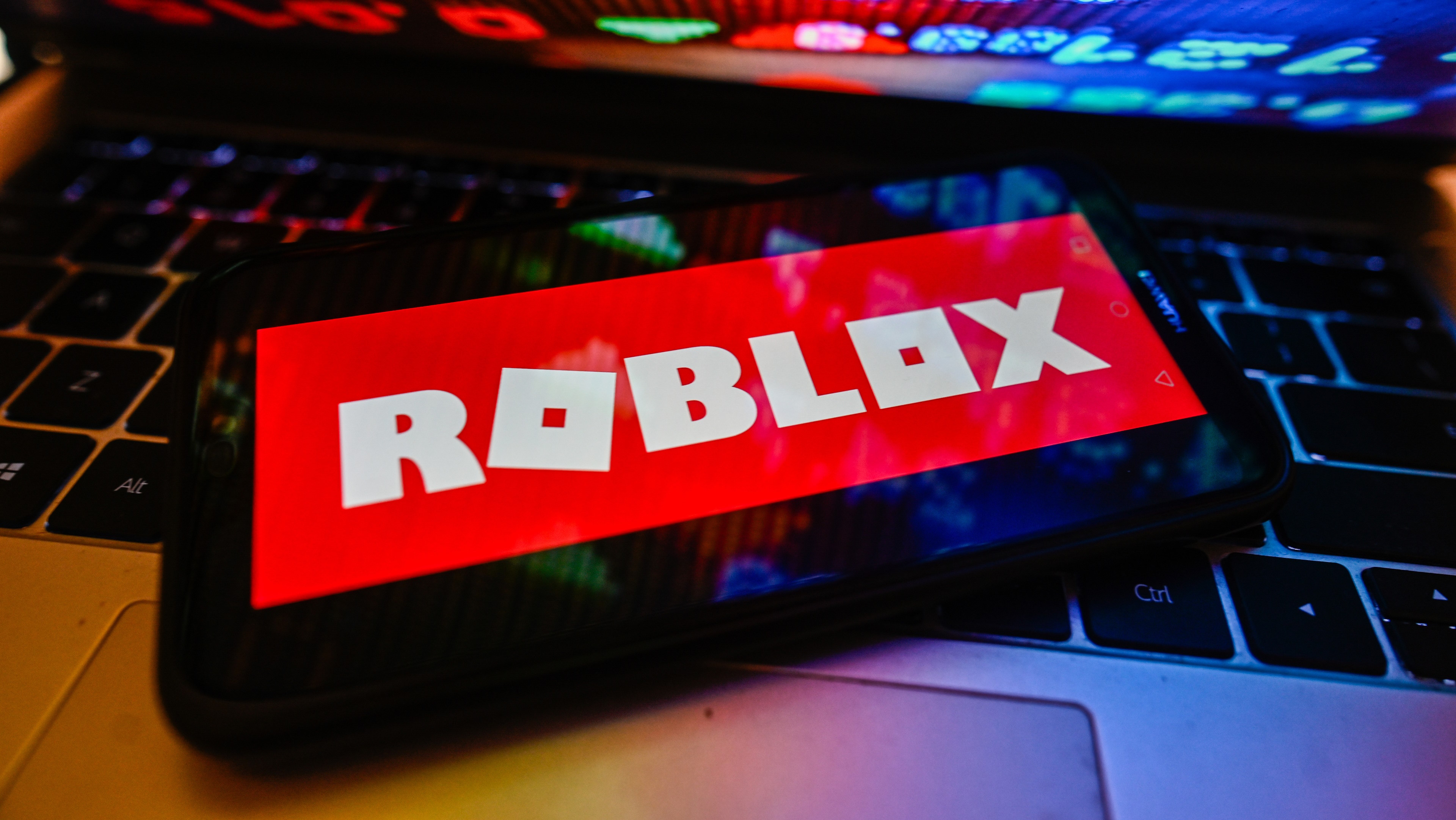 POLAND - 2023/11/09: In this photo illustration a Roblox logo is displayed on a smartphone with stock market percentages on a laptop. (Photo Illustration by Omar Marques/SOPA Images/LightRocket via Getty Images)