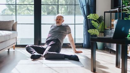 Man performs the 90/90 stretch at home