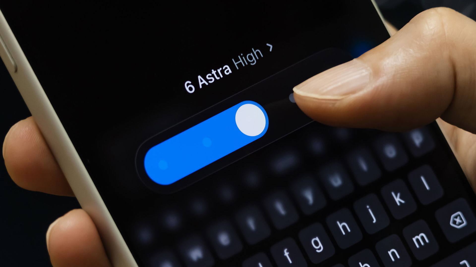 A person holds a smartphone with a dark screen that reads