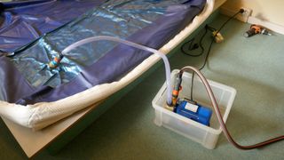 An empty water bed being filled up next to a waterbed heater