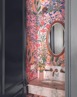 A small powder room with a pink wallpaper