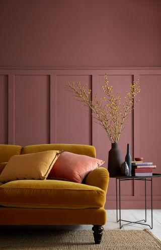 Living room with yellow sofa, side table, panelling and above painted in red brown