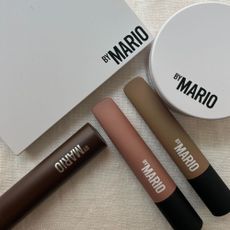 A selection of Makeup By Mario products on a white linen background