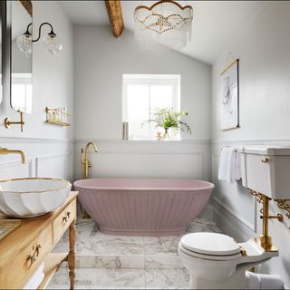 bathroom with white wall and fluted pink bathtub and washbasin and toilet and marble flooring