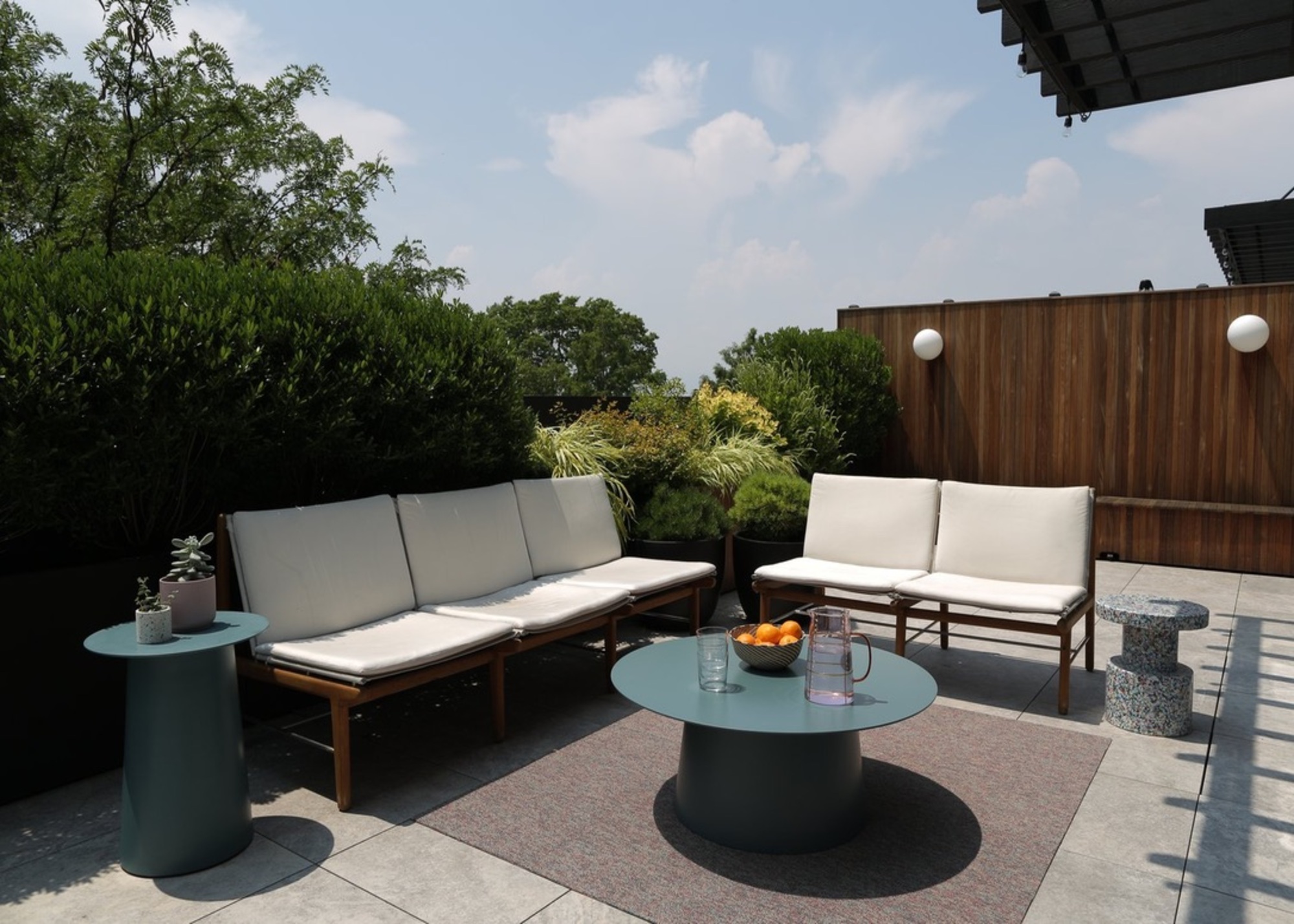 A patio area with pavers, a wooden fence, and white garden furniture