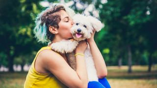Young woman kissing dog outside 