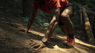 A man climbing up a steep slope wearing the Amazfit T-Rex 3 on his left wrist