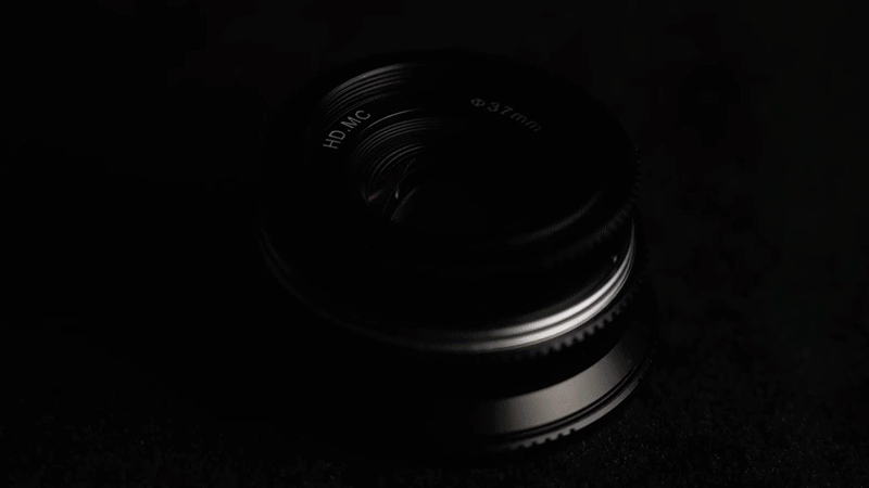 Pergear 25mm f/1.7 lens, in pitch blackness, with moving light highlighting the edges