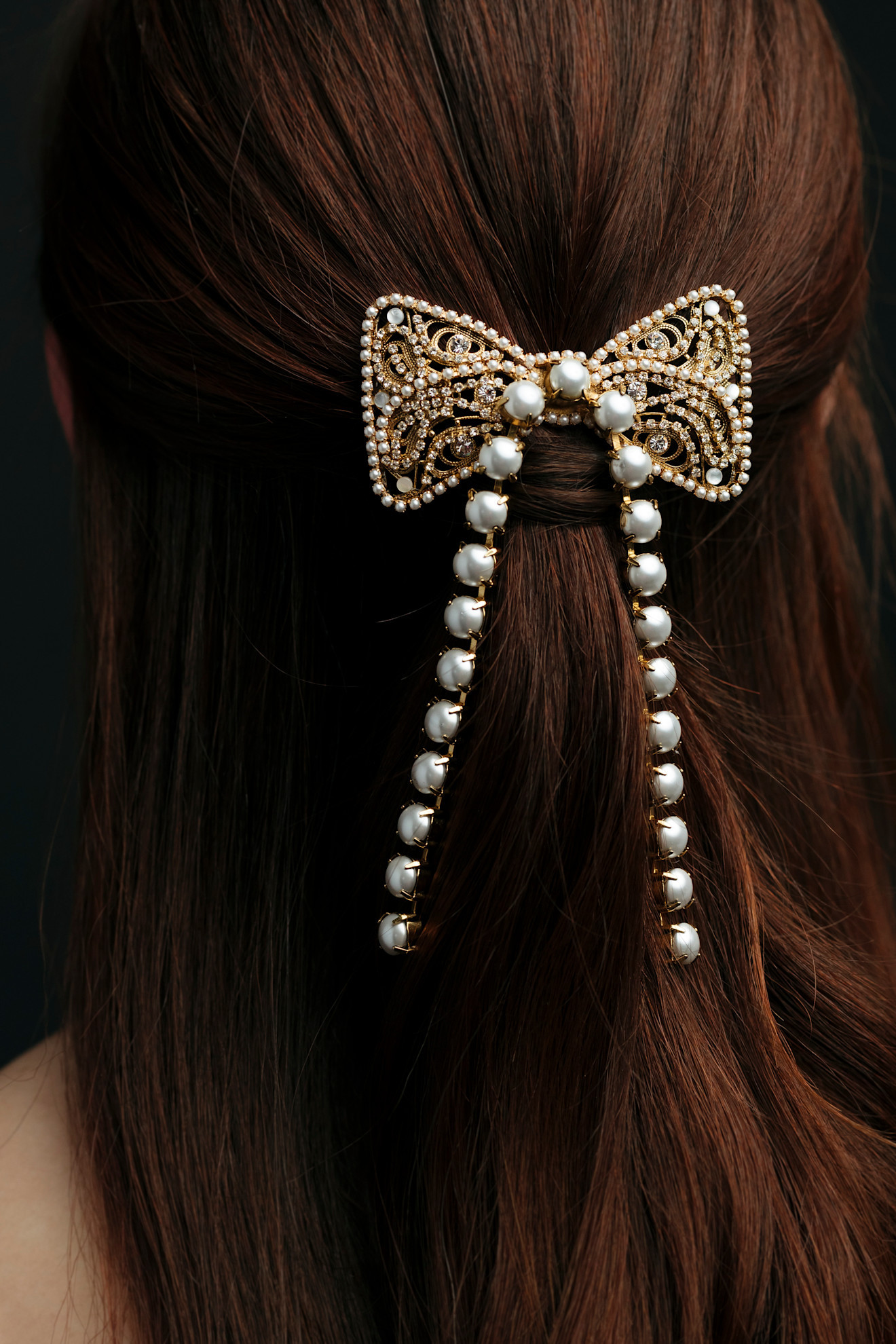 model with dark brunette hair wearing a gold hair bow clip featuring pearl embellishments