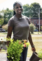 Marlene Pantin, wearing brown t-shirt and holding plants in each hand