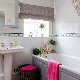 white tiles bathroom with bathtub and clothes basket