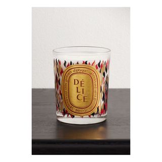 Diptique scented candle in glass vessel with gold, red and black flame pattern