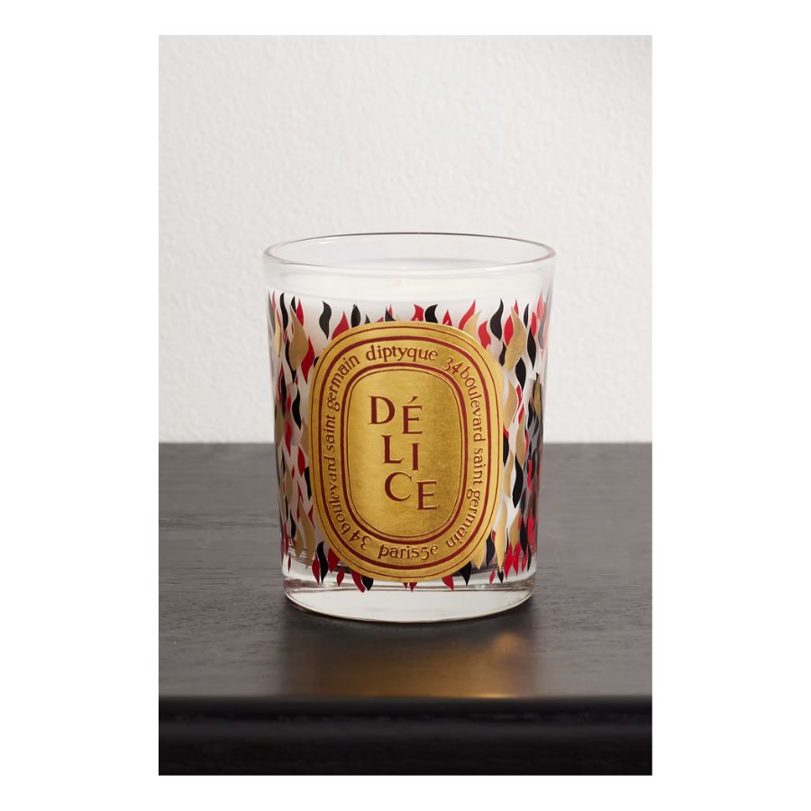 Diptique scented candle in glass vessel with gold, red and black flame pattern