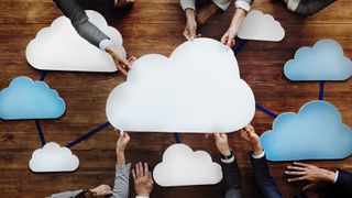 People sitting around a table, reaching in to hold a network of clouds