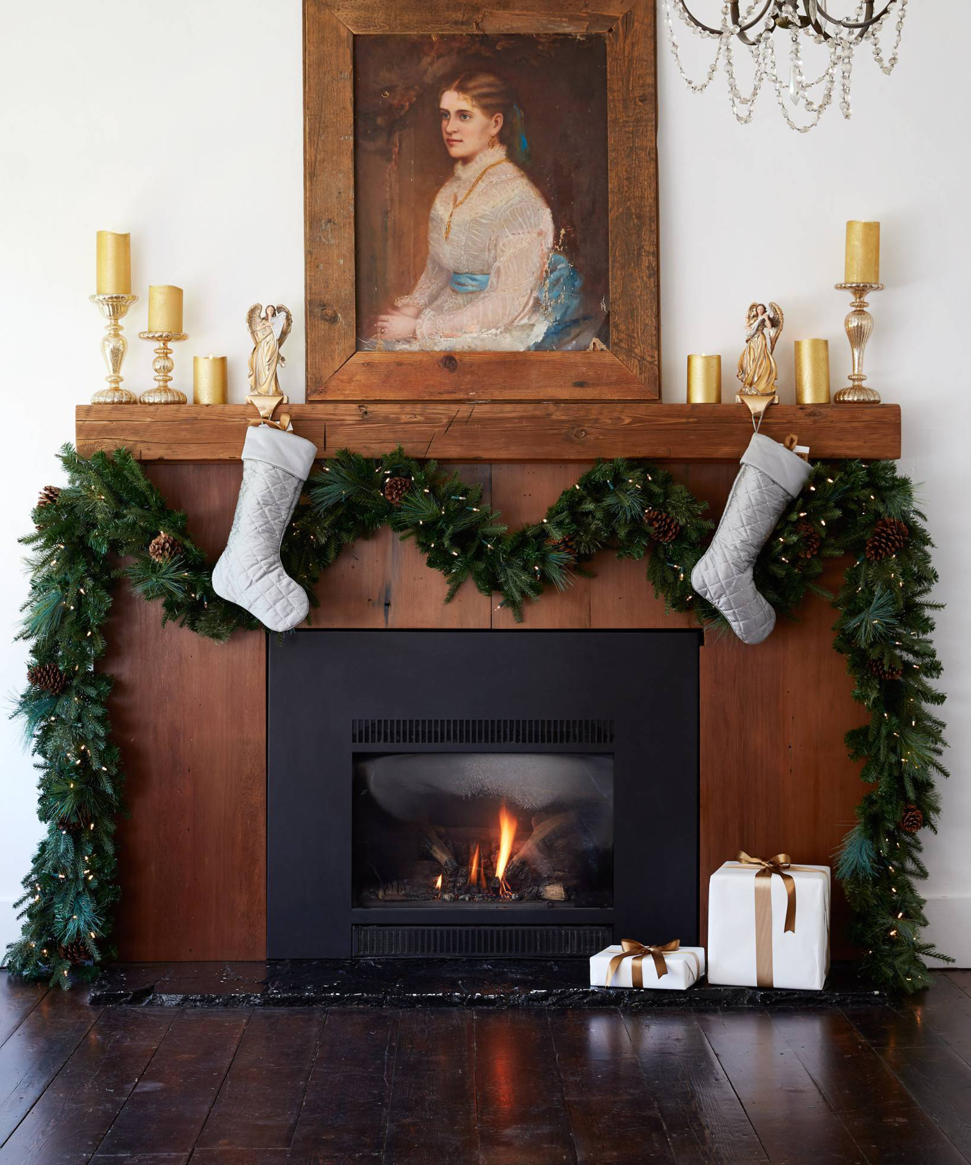 A living room with mixed evergreen garland with pinecones with framed wall art