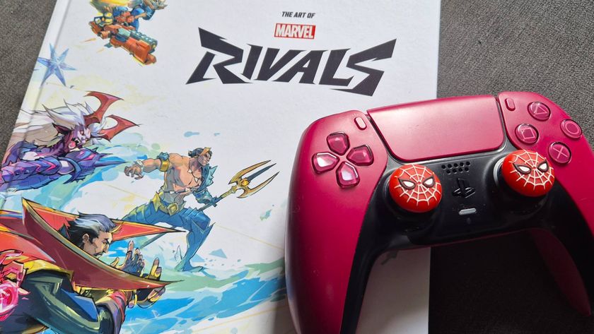 Photo by Rosalie Newcombe of a red PS5 DualSense controller with Spider-man stick grips sitting on the Art of Marvel Rivals book.