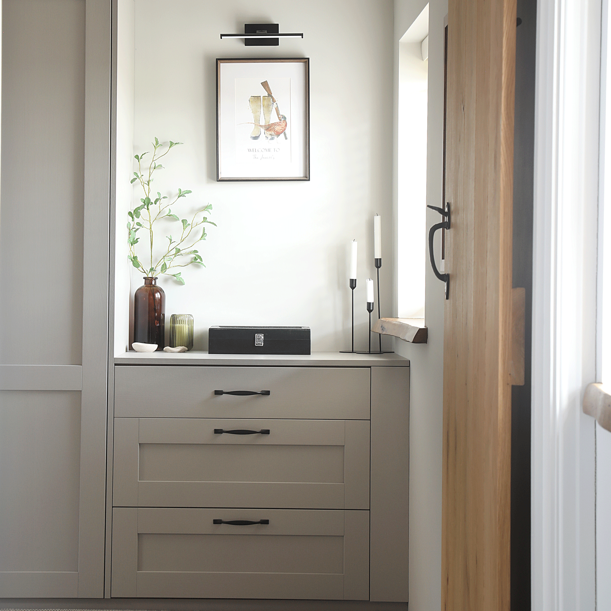 a corner of a bedroom beside a window with fitted wardrobes and drawers that create a mini dressing area