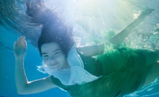 Björk under water in green and white dress
