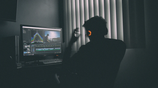 A man wearing headphones using Adobe Premiere Pro video editing software in a home studio