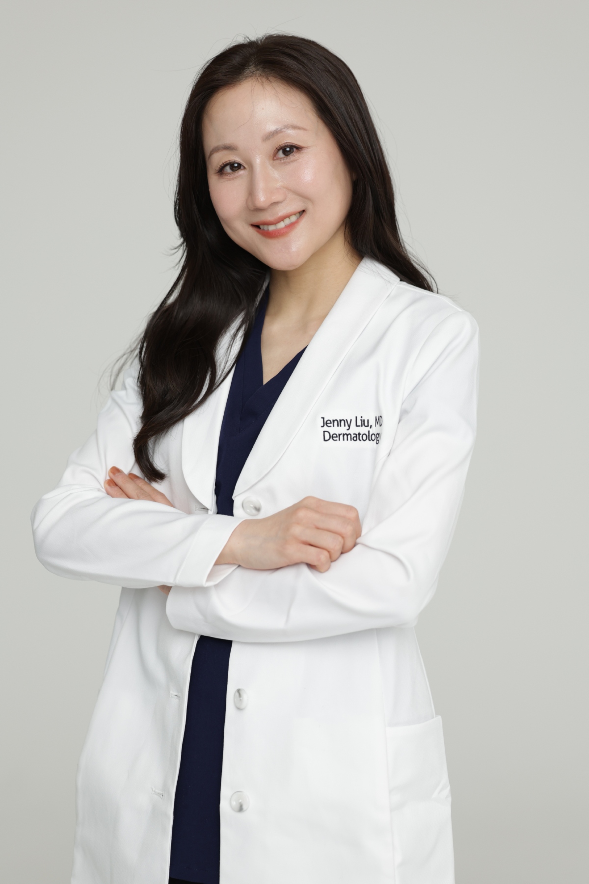 an asian woman in a white lab coat and blue scrubs