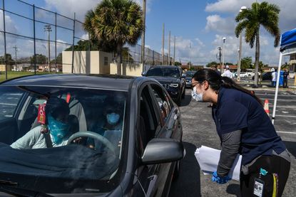 People collect unemployment forms at a drive thru collection point outside John F. Kennedy Library