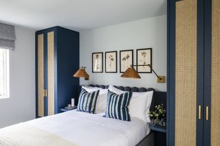 bedroom with blue/rattan wardrobes, built in side tables, rattan wall lights, artwork, blind