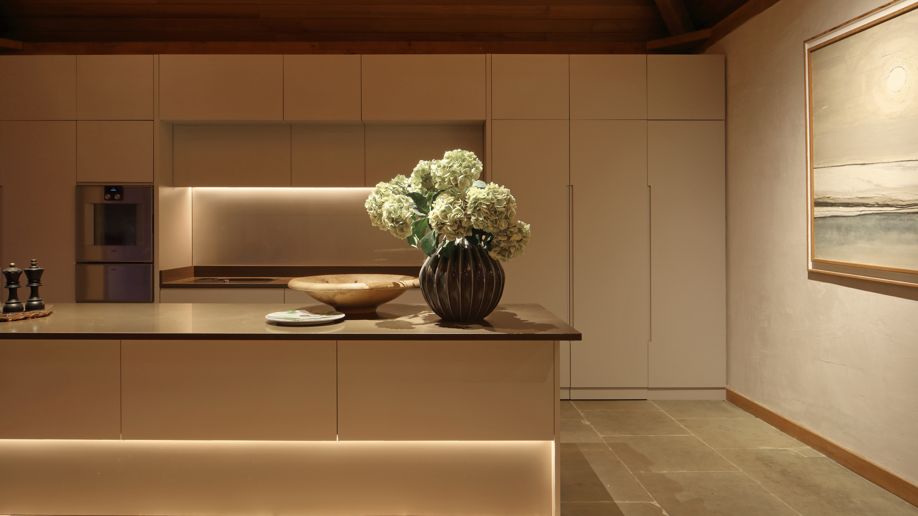 beautiful, neutral kitchen with handless cabinetry and simple finishes, there is under-cabinet LED lighting throughout, for a warm even glow