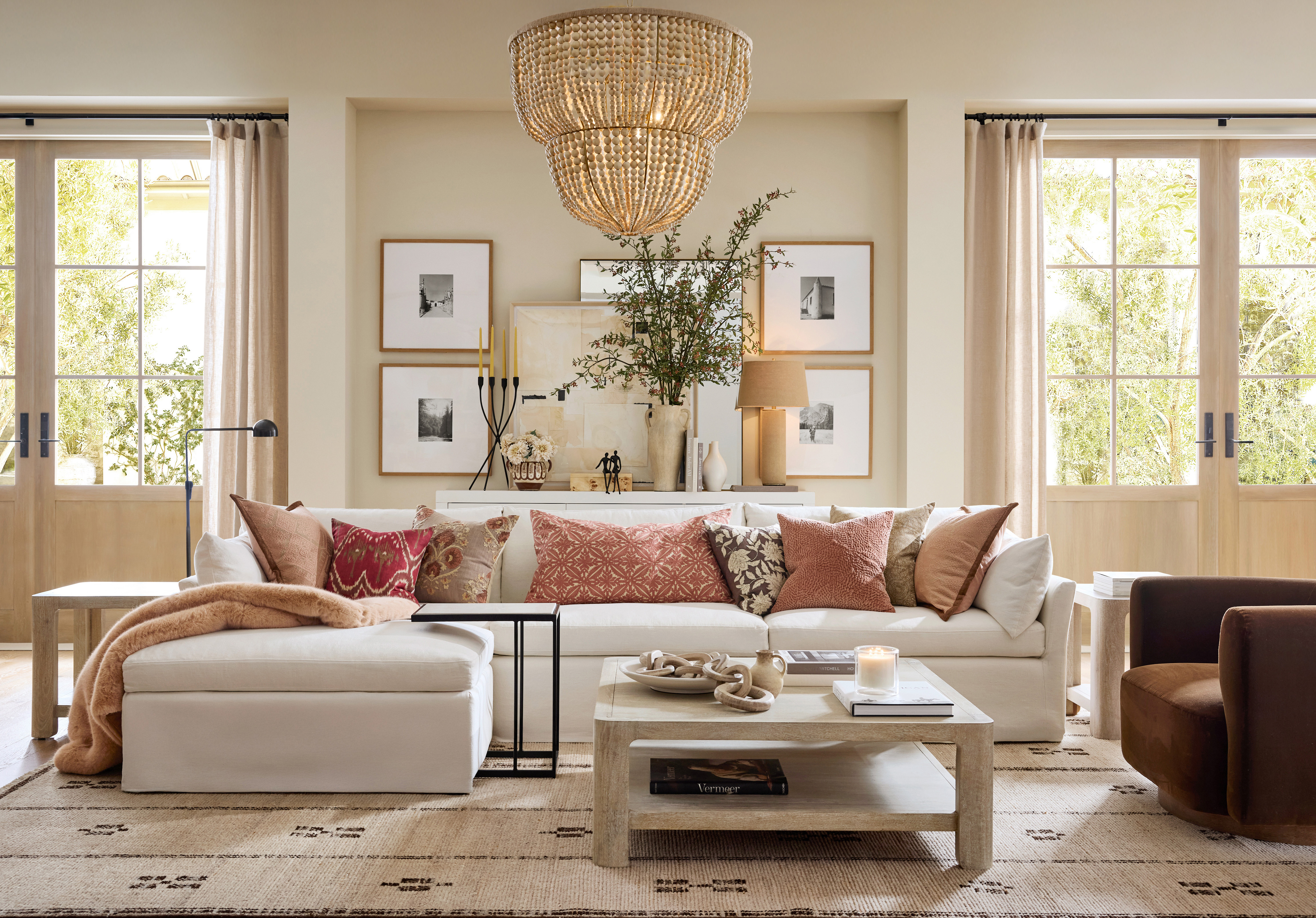 a modern living space with an l-shaped white sofa, coffee table, brown armchair and large rattan ceiling light