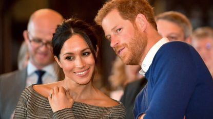 Prince Harry whispers to Meghan Markle as they watch a dance performance by Jukebox Collective in the banqueting hall during a visit to Cardiff Castle on January 18, 2018 in Cardiff, Wales