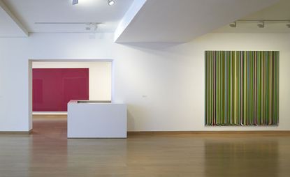 A gallery with a colourful painting made of vertical lines on the wall.