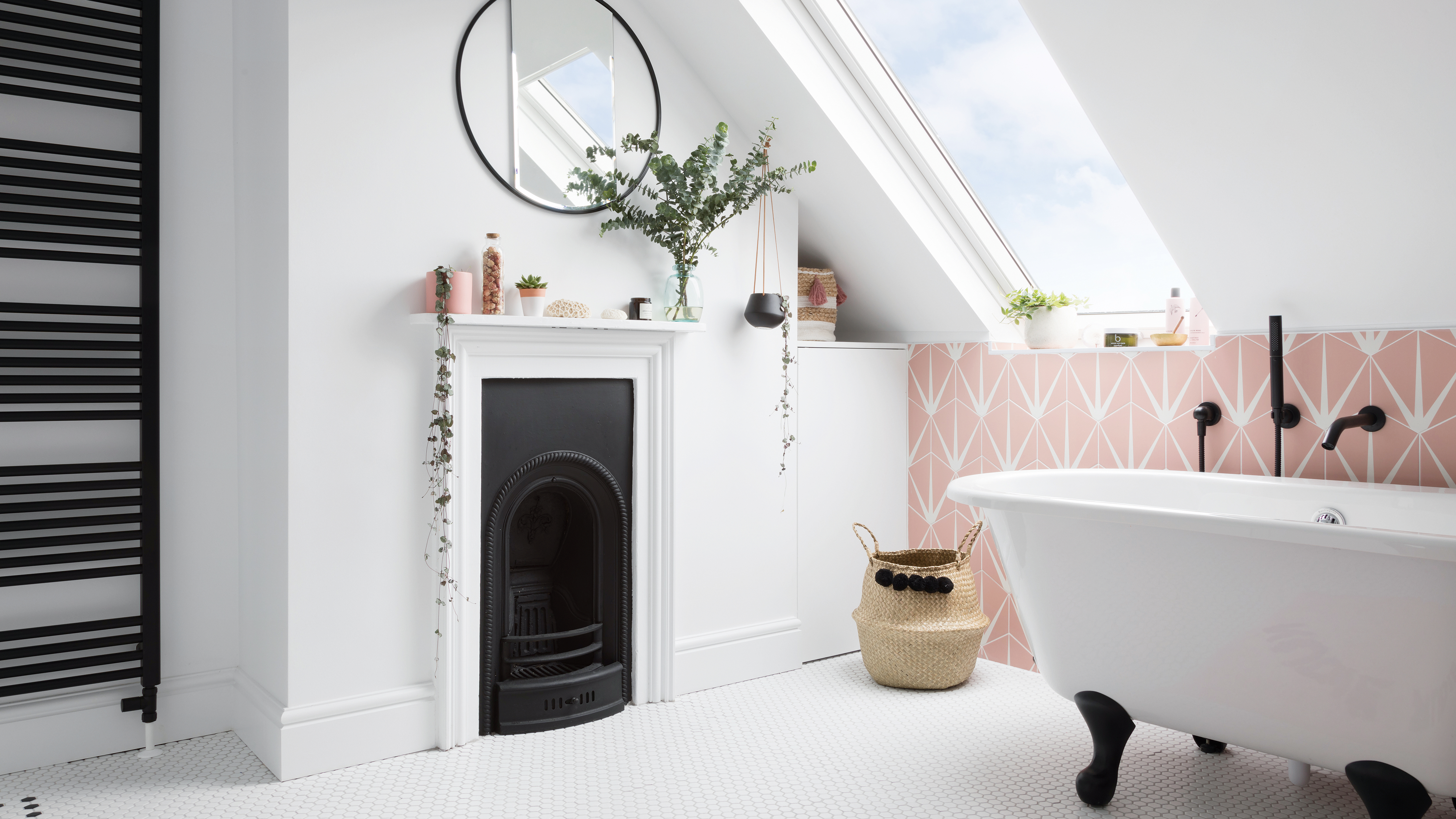 white bathroom with pink geo wall tiles and a sloped ceiling with a velux window