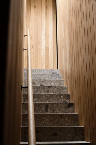 Grey marble stair case with oak slated walls