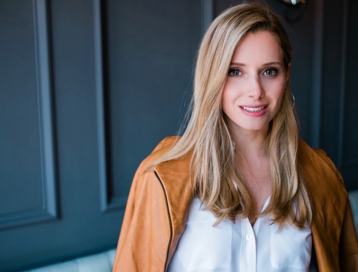 a white woman with brown hair in a tan jacket and white shirt