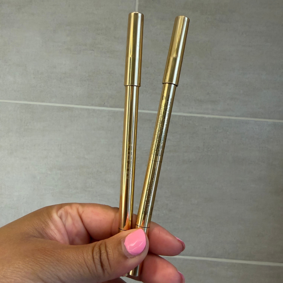 Hand holding two empty Merit Beauty Signature Lip Liners in 'Coupe&amp;#769;'