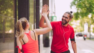 Runners high-fiving after exercising as partners