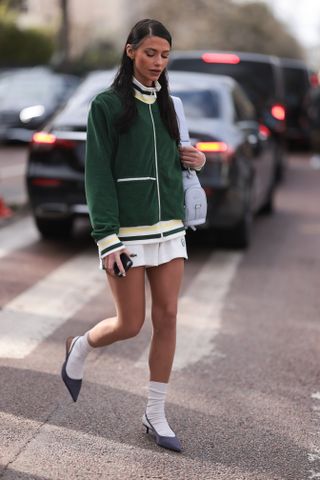 Heloise Agostinelli seen wearing a green and white Lacoste tennis skirt, green Lacoste jacket, white socks, grey heels, Lacoste white leather bag outside Lacoste Show during the Womenswear Fall/Winter 2024/2025 as part of Paris Fashion Week on March 05, 2024 in Paris, France.