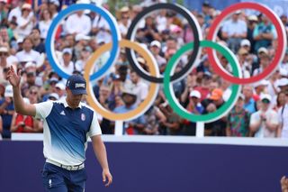 Victor Perez raises his hands in front of the Olympic rings