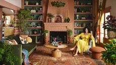 Justina Blakeney in a yellow dress sat in a maximalist terracotta living room